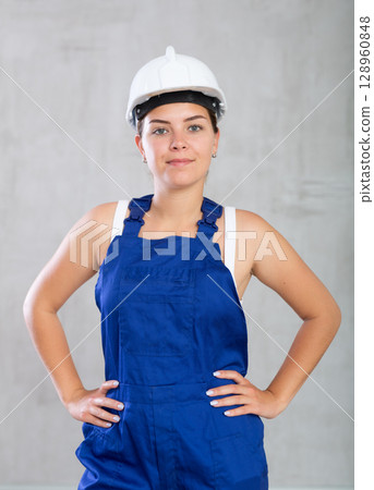 Young woman posing in work overalls in studio 128960848