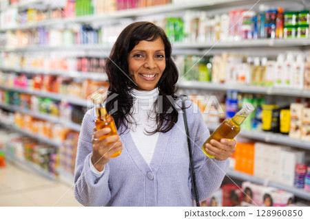 Latin american woman looking for haircare products at cosmetics shop Latin american woman looking for haircare products at cosmetics shop 128960850