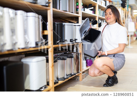 Woman choosing trash can at hardware store Woman choosing trash can at hardware store 128960851