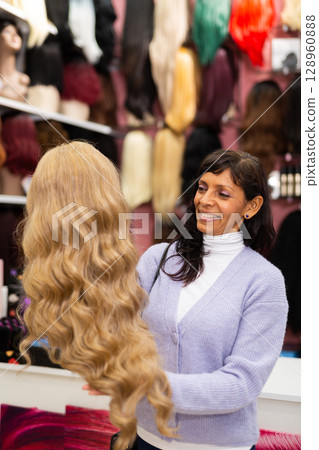 Woman choosing natural wig at specialty boutique 128960888
