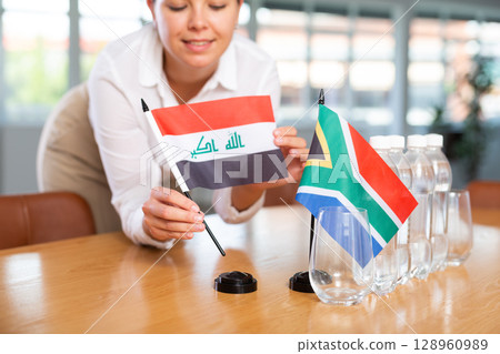 Blurry girl set midget flags of South Africa and Iraq before international negotiations 128960989