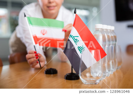 Unrecognizable girl sets midget flags of Iraq and Iran before international negotiations Unrecognizable girl sets midget flags of Iraq and Iran before international negotiations 128961046