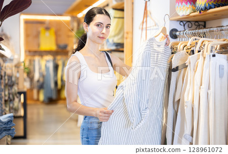 Girl customer chooses blouse in branded store Girl customer chooses blouse in branded store 128961072