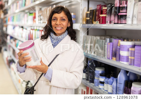 Female searching for hair mask in cosmetics shop 128961078