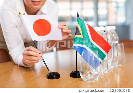 Blurry girl set midget flags of South Africa and Japan before international negotiations 128961088
