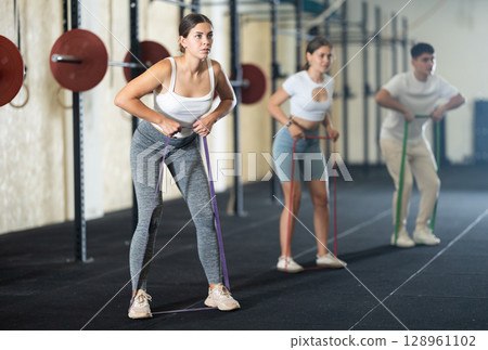 Group CrossFit classes - people doing sports with elastic bands Group CrossFit classes - people doing sports with elastic bands 128961102