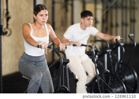 Young woman exercising on exercise bike in gym Young woman exercising on exercise bike in gym 128961110