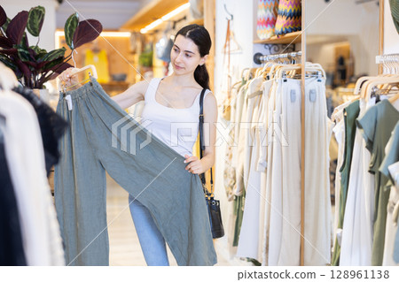 Woman choosing linen clothes in store 128961138