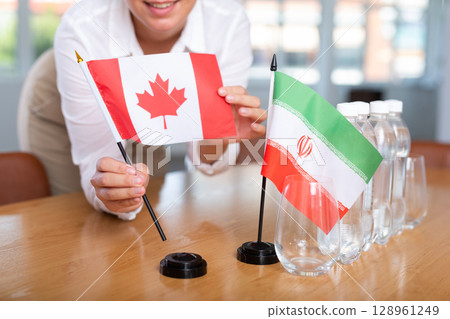 Businesswoman arranging the flags of Iran and Canada for presentation and negotiations 128961249