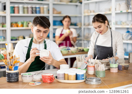 Man painting with brush on handmade clay cup 128961261