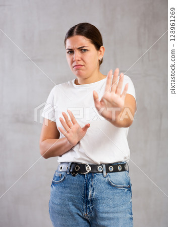 Irritated young woman posing crossly against gray background 128961269