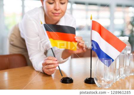 Blurry girl set midget flags of Netherlands and Germany before international negotiations 128961285