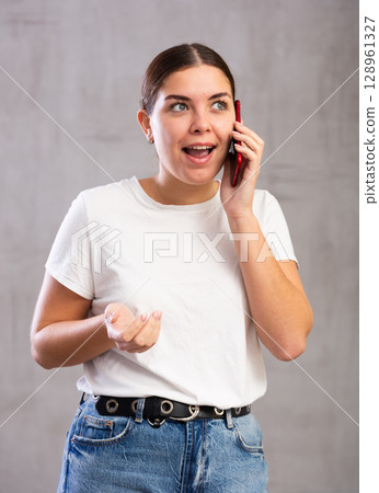 Surprised young woman talking on mobile phone Surprised young woman talking on mobile phone 128961327
