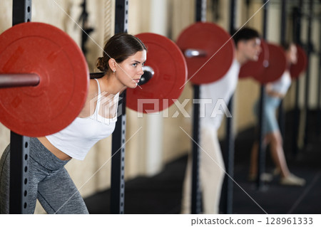 Young woman training with barbell in gym Young woman training with barbell in gym 128961333