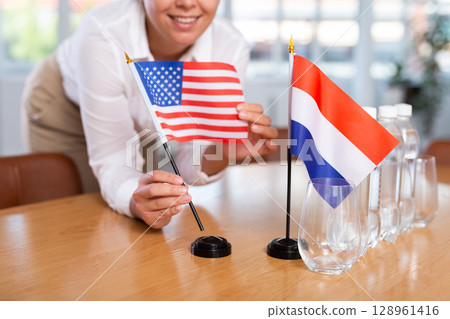 Blurry girl set midget flags of Netherlands and USA before international negotiations 128961416