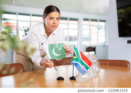Businesswoman arranging the flags of Pakistan and South Africa for presentation and negotiations Businesswoman arranging the flags of Pakistan and South Africa for presentation and negotiations 128961435