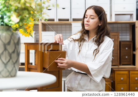Female choosing wooden drawer in furniture store Female choosing wooden drawer in furniture store 128961440