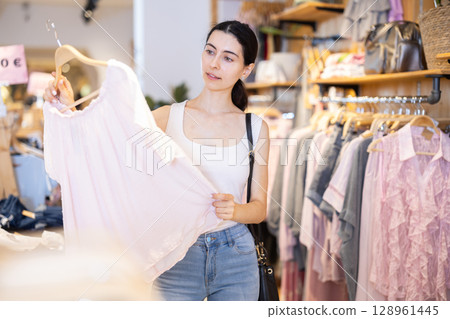 Girl customer chooses blouse in branded store 128961445