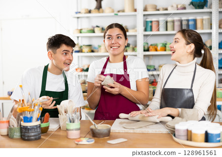 Two young women and young man making pottery Two young women and young man making pottery 128961561