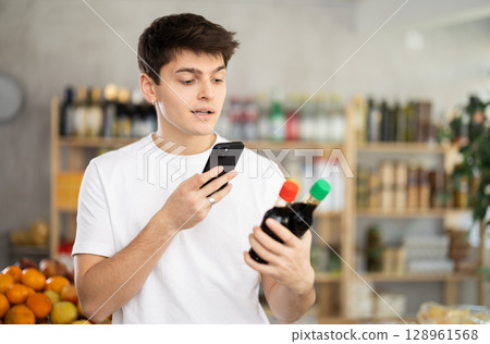 Guy using mobile app to pay for soy sauce in grocery store 128961568