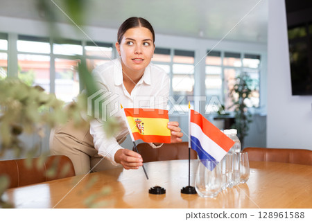 Young lady sets miniatures flags of Netherlands and Spain for international negotiations Young lady sets miniatures flags of Netherlands and Spain for international negotiations 128961588