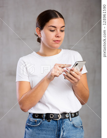 Calm young woman looking interestedly at mobile 128961590