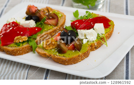 Toasts with guacamole, fresh vegetables, feta cheese Toasts with guacamole, fresh vegetables, feta cheese 128961592