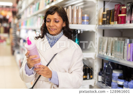Woman choosing hair shampoo in cosmetics store 128961601