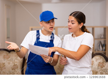 Master discusses with the young landlady of the apartment the plan of repair work Master discusses with the young landlady of the apartment the plan of repair work 128961688
