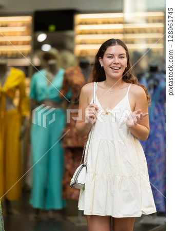 Young girl in white dress is looking for something at street market - looking at goods with interest 128961745