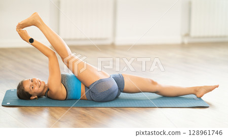 Lover of active lifestyle on yoga mat perform doing Parivritta Janu Shirshasana in gym Lover of active lifestyle on yoga mat perform doing Parivritta Janu Shirshasana in gym 128961746