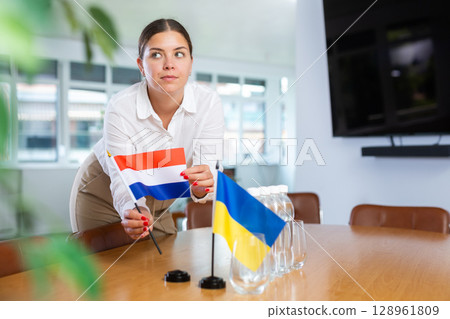 Businesswoman placing flags of Netherlands and Ukraine on negotiating table Businesswoman placing flags of Netherlands and Ukraine on negotiating table 128961809