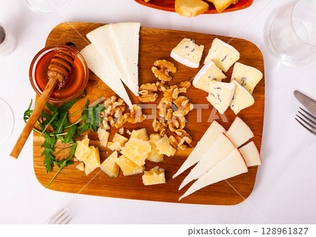 Cheese board served with honey over white background Cheese board served with honey over white background 128961827