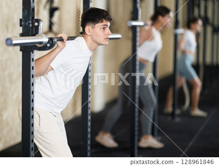 Young guy training with barbell in gym 128961846