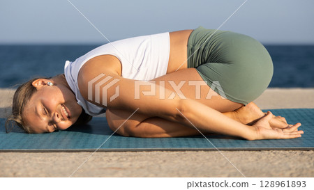 Yoga training on seashore - girl in dog pose on mats 128961893