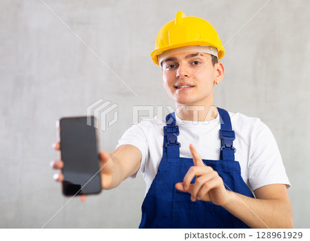 Smiling young guy posing in uniform with phone in his hand 128961929