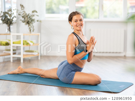 Positive fit girl performing Half Pigeon Pose during yoga training Positive fit girl performing Half Pigeon Pose during yoga training 128961950
