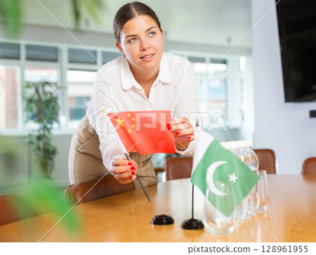 Young woman putting flags of China and Pakistan on table in office Young woman putting flags of China and Pakistan on table in office 128961955