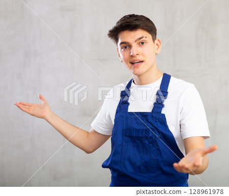 Emotions, people and positive concept - man in blue protective overalls expresses different on gray background Emotions, people and positive concept - man in blue protective overalls expresses different on gray background 128961978