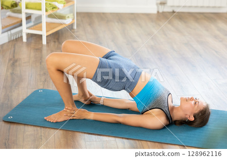 Young girl performing shoulder supported bridge in yoga studio 128962116