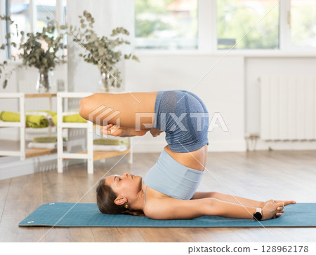Lover of active lifestyle on yoga mat perform doing shoulder stand in gym 128962178