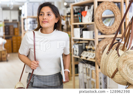 Woman designer choosing accessories in shop for decor Woman designer choosing accessories in shop for decor 128962398