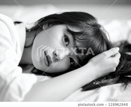 Monochrome photo of a woman lying on a bed 128962848