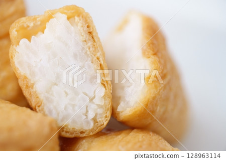The contrast between the soft brown of the plump fried tofu and the glossy white of the vinegared rice (before thawing) 128963114