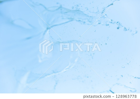 水花在藍天上蔓延,透明的水滴以流動的圖案落下 水花在藍天上蔓延,透明的水滴以流動的圖案落下 128963778