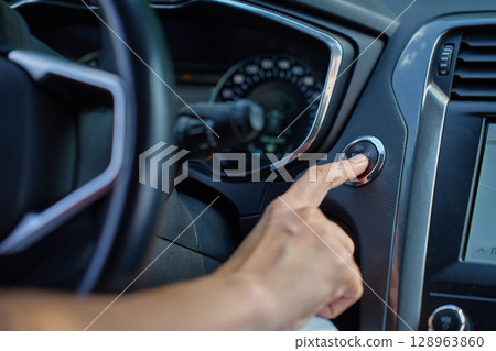 Close-up of hand pressing start button to turn on car engine. Keyless ignition system in modern car Close-up of hand pressing start button to turn on car engine. Keyless ignition system in modern car 128963860