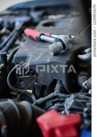 Close-up of wrench socket tool lying on car engine during maintenance work. Vehicle repair concept Close-up of wrench socket tool lying on car engine during maintenance work. Vehicle repair concept 128963870