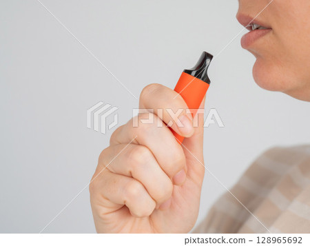Caucasian woman smoking disposable vape.  128965692