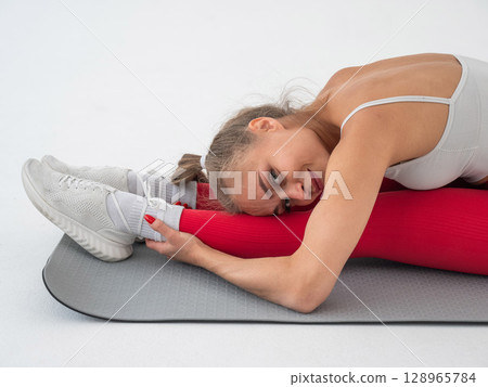 Caucasian woman doing stretching and doing side splits on white background. Caucasian woman doing stretching and doing side splits on white background. 128965784