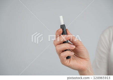 Faceless woman holding tobacco heating system. Faceless woman holding tobacco heating system. 128965913